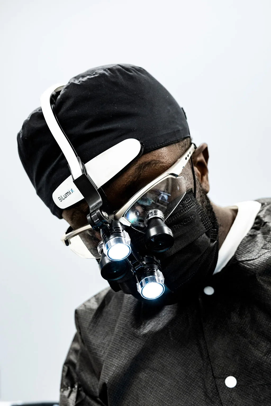 Dr. Ennuson wearing magnification loupes, lit from the window